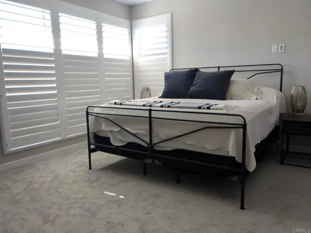 a bed sitting in a bedroom next to a window and dresser