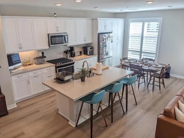 a kitchen with stainless steel appliances granite countertop table chairs microwave and sink