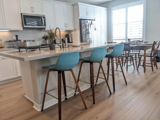 a kitchen with granite countertop a table chairs microwave and cabinets