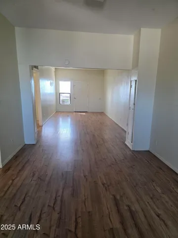 a view of empty room with window and wooden floor