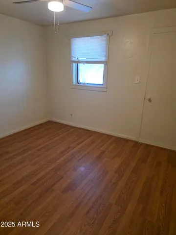 an empty room with wooden floor chandelier fan and windows