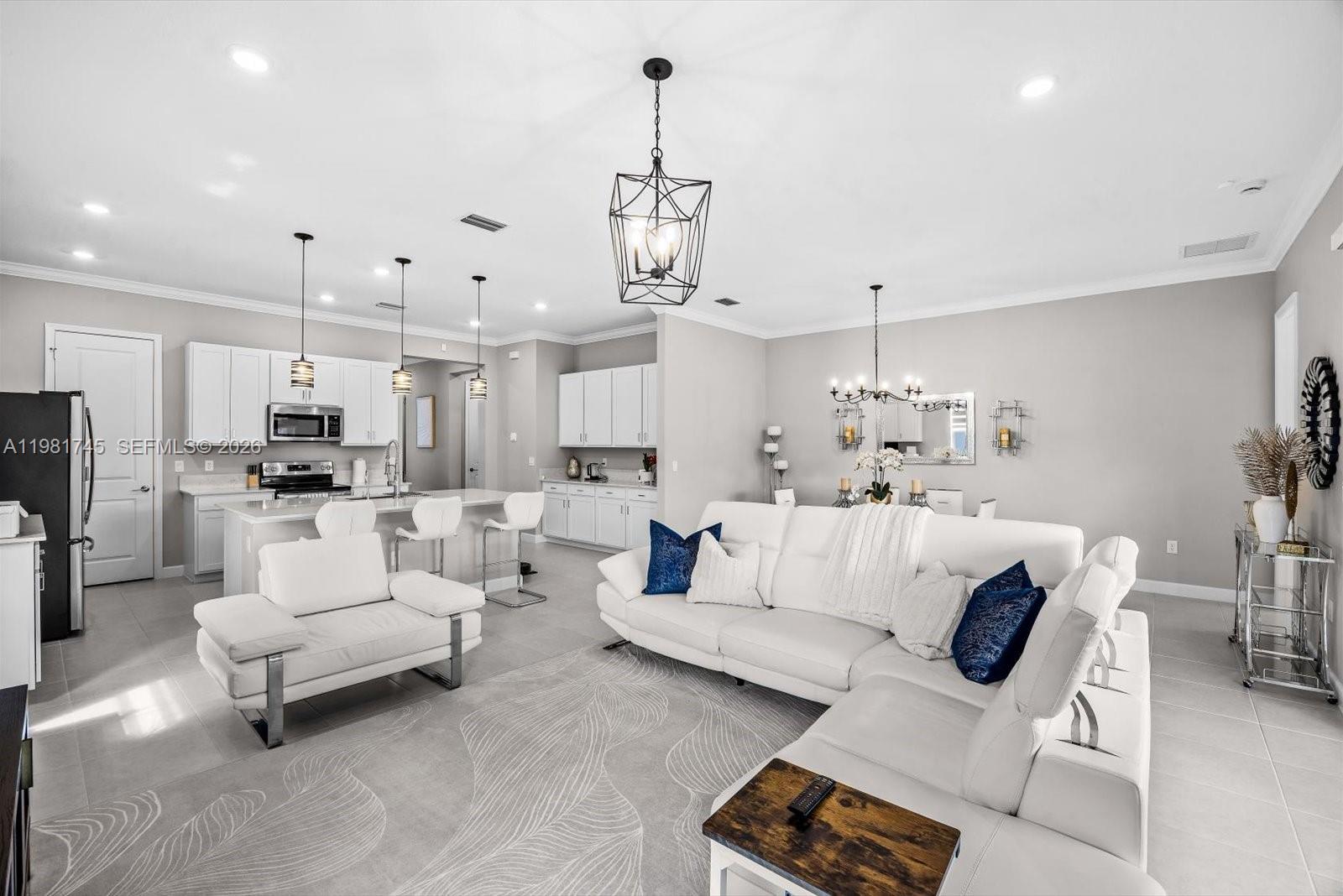 1204 Southeast Woodbine Road Port St. Lucie, FL 34984 - Photo 17 of 46 a living room with furniture kitchen view and a chandelier