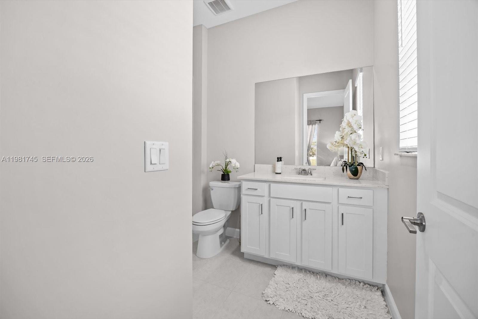 1204 Southeast Woodbine Road Port St. Lucie, FL 34984 - Photo 30 of 46 a bathroom with a granite countertop toilet sink and mirror