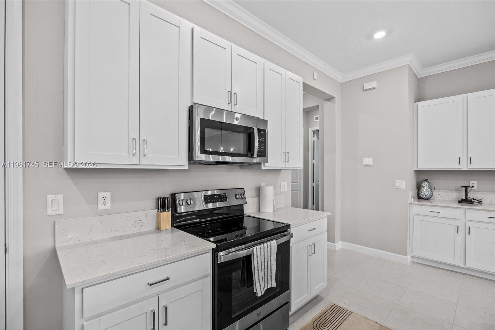 1204 Southeast Woodbine Road Port St. Lucie, FL 34984 - Photo 10 of 46 a kitchen with white cabinets and stainless steel appliances