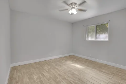 a view of an empty room with a window and wooden floor