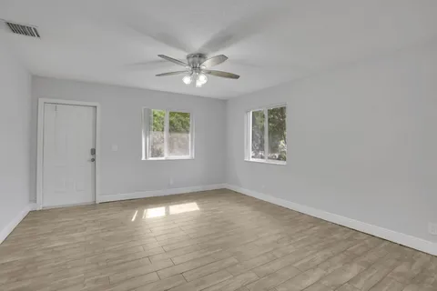 a view of empty room with wooden floor and fan