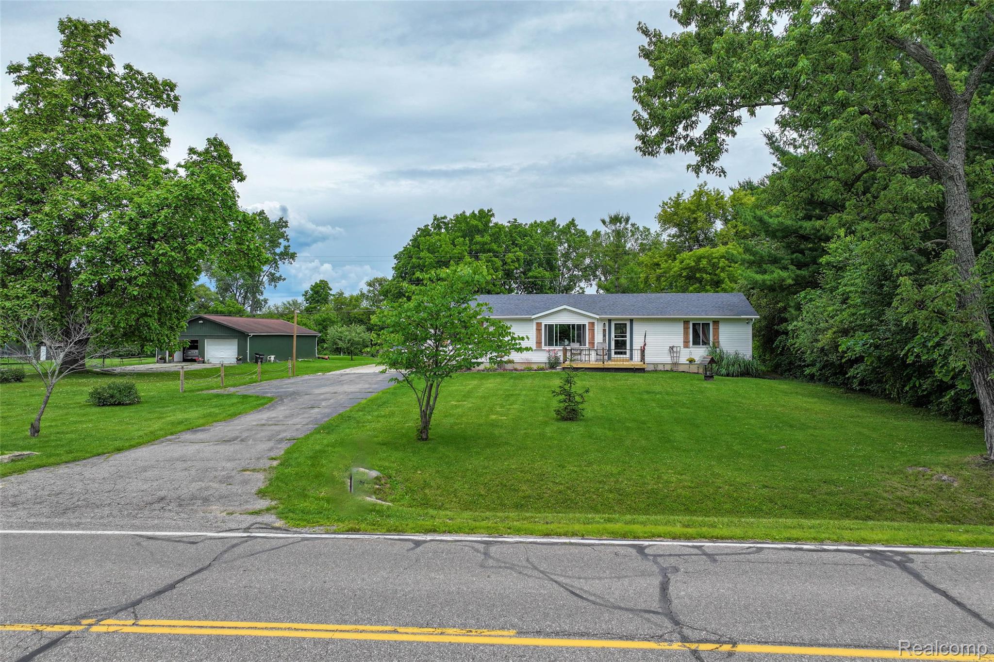 1336 West Hurd Road Clio, MI 48420 - Photo 36 of 43 White-sided ranch home featuring a covered front porch, a gravel driveway, and a detached garage with a green exterior