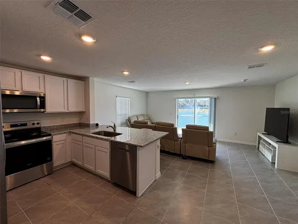 a kitchen with stainless steel appliances granite countertop a sink a stove top oven a counter space and cabinets