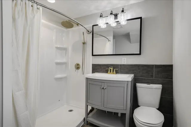 a bathroom with a toilet sink vanity and mirror
