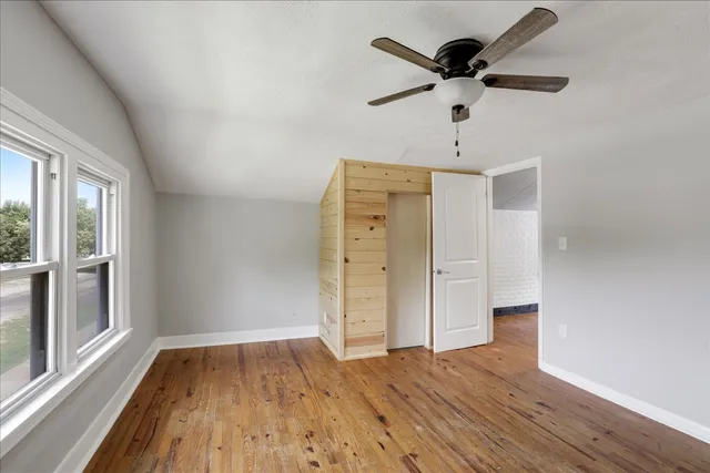 a view of empty room with wooden floor and fan