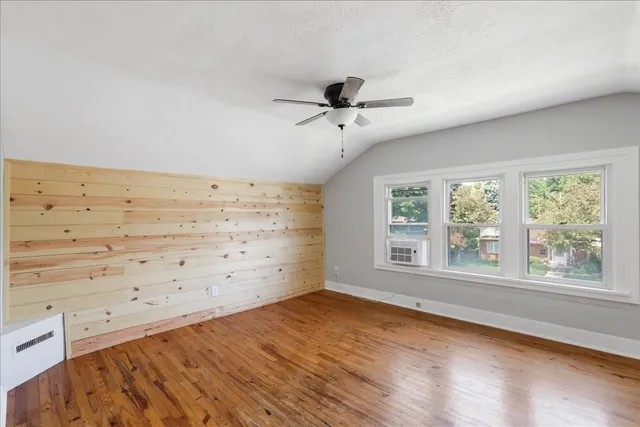 a view of empty room with wooden floor and fan