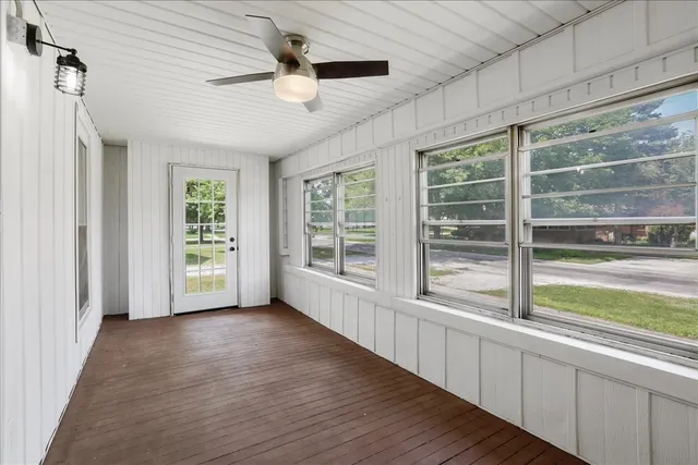 a view of empty room with wooden floor and fan