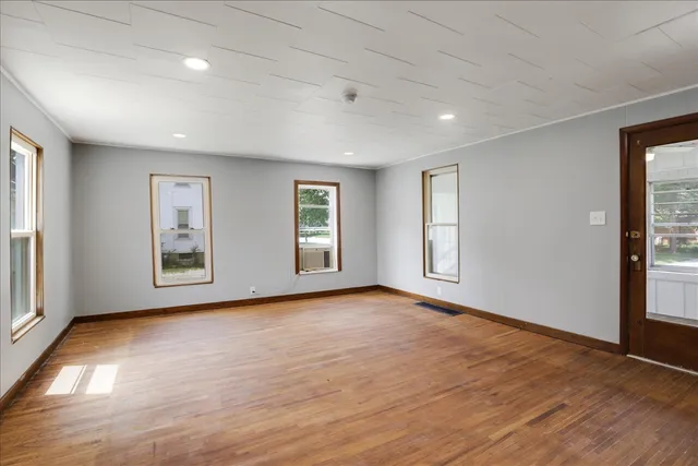 a view of an empty room with window and wooden floor