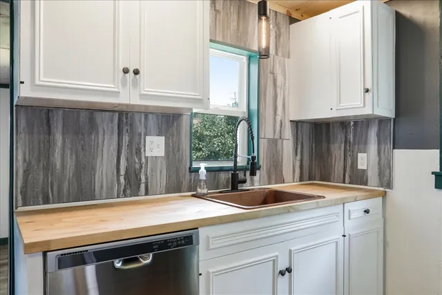 a kitchen with granite countertop a sink and a white cabinets