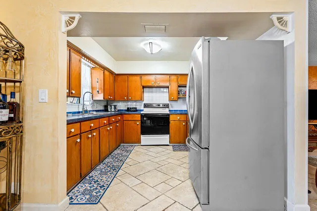a large kitchen with stainless steel appliances granite countertop a refrigerator and a sink