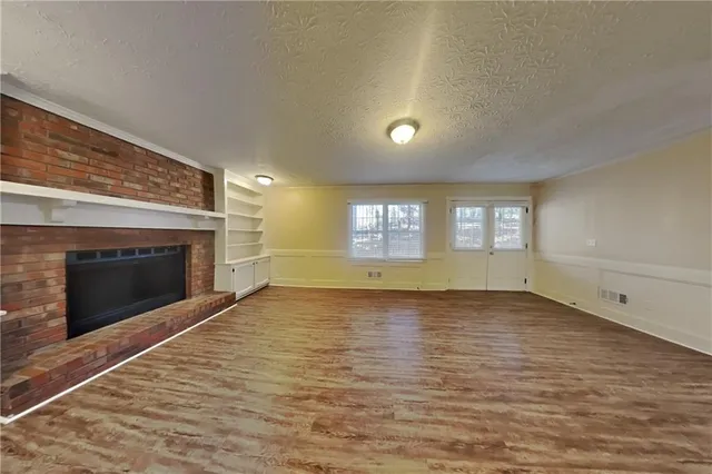 a view of empty room with wooden floor and fireplace