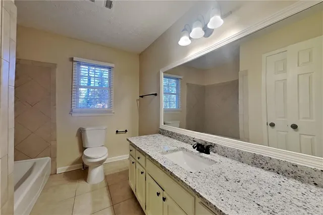 a bathroom with a granite countertop sink a toilet and a large mirror
