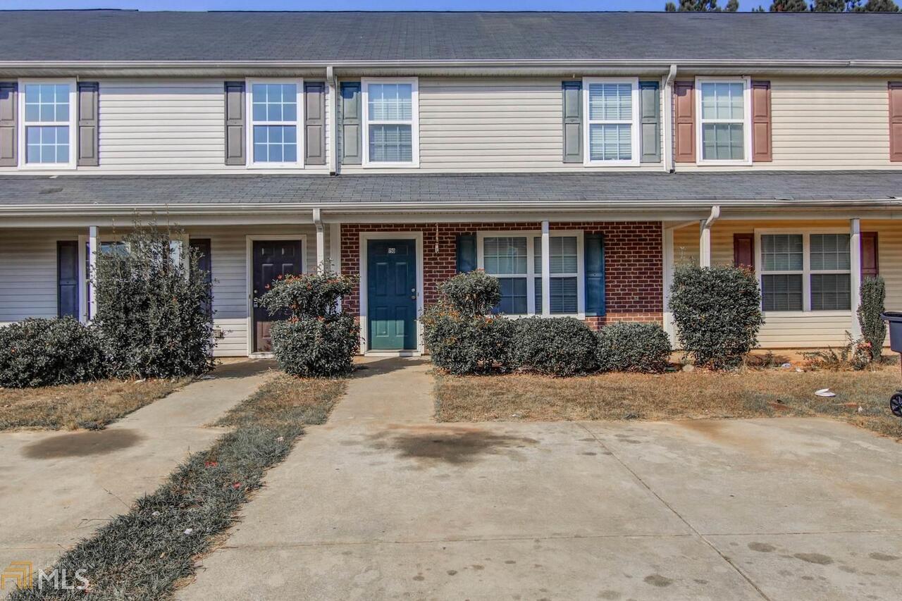 a view of a brick house with yard and plants