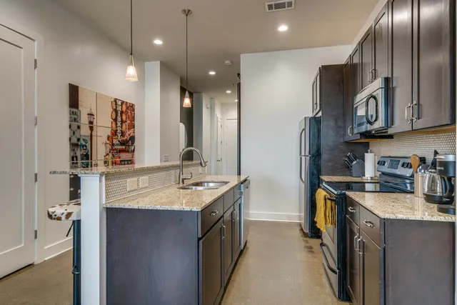 a kitchen with stainless steel appliances granite countertop a sink a stove and a refrigerator