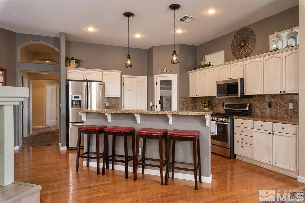 1325 South Fox Glen Court Reno, NV 89521 - Photo 3 of 25 a kitchen with stainless steel appliances granite countertop a stove a sink a microwave a dining table and chairs with wooden floor
