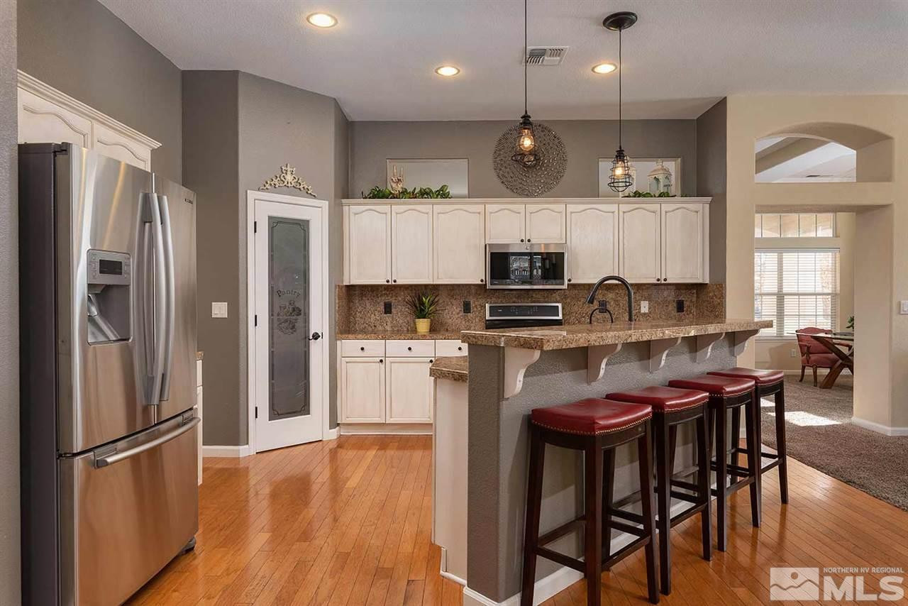 1325 South Fox Glen Court Reno, NV 89521 - Photo 4 of 25 a kitchen with stainless steel appliances granite countertop a refrigerator a stove a sink a dining table and chairs with wooden floor