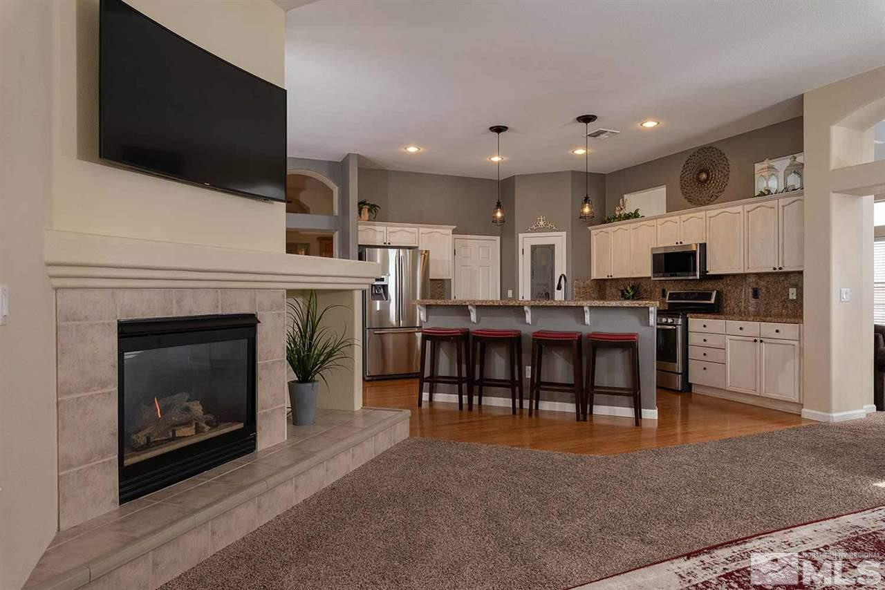 1325 South Fox Glen Court Reno, NV 89521 - Photo 8 of 25 a open kitchen that has a fireplace a flat screen tv a island and stainless steel appliances