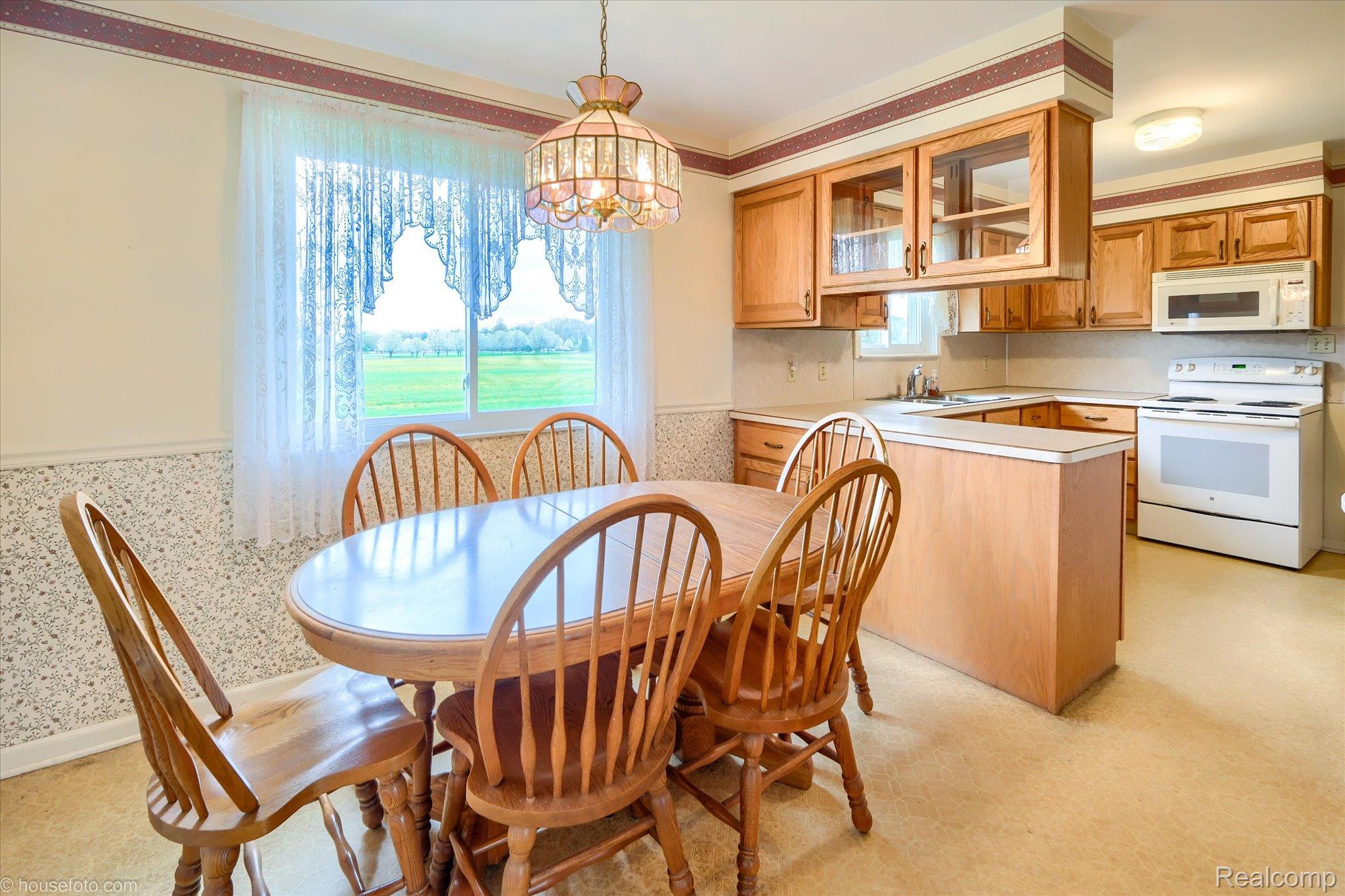 6080 Shattuck Road Saginaw, MI 48603 - Photo 13 of 35 Dining area with a wainscoted wall, wallpapered walls, and a chandelier