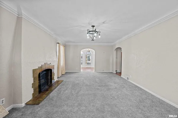 a view of a livingroom with a fireplace a ceiling fan and windows