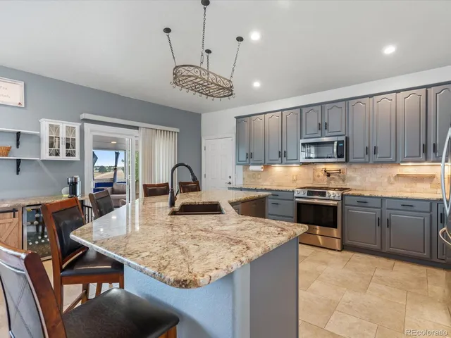 a kitchen with kitchen island granite countertop wooden cabinets a stove a sink and a center island