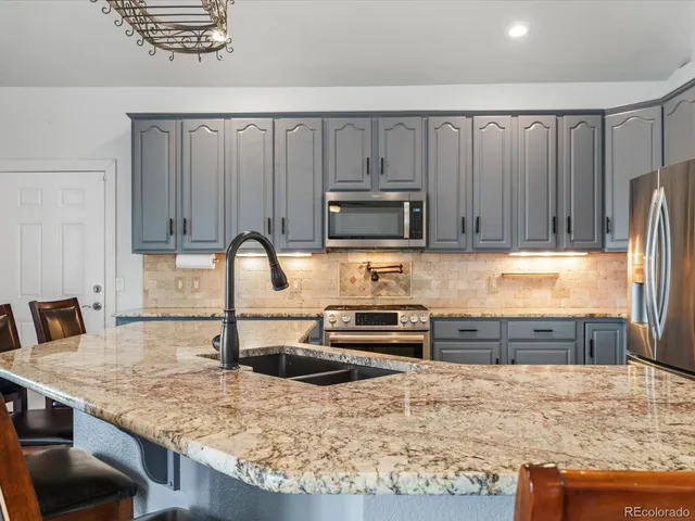 a kitchen with kitchen island granite countertop a stove top oven a sink a dining table and chairs