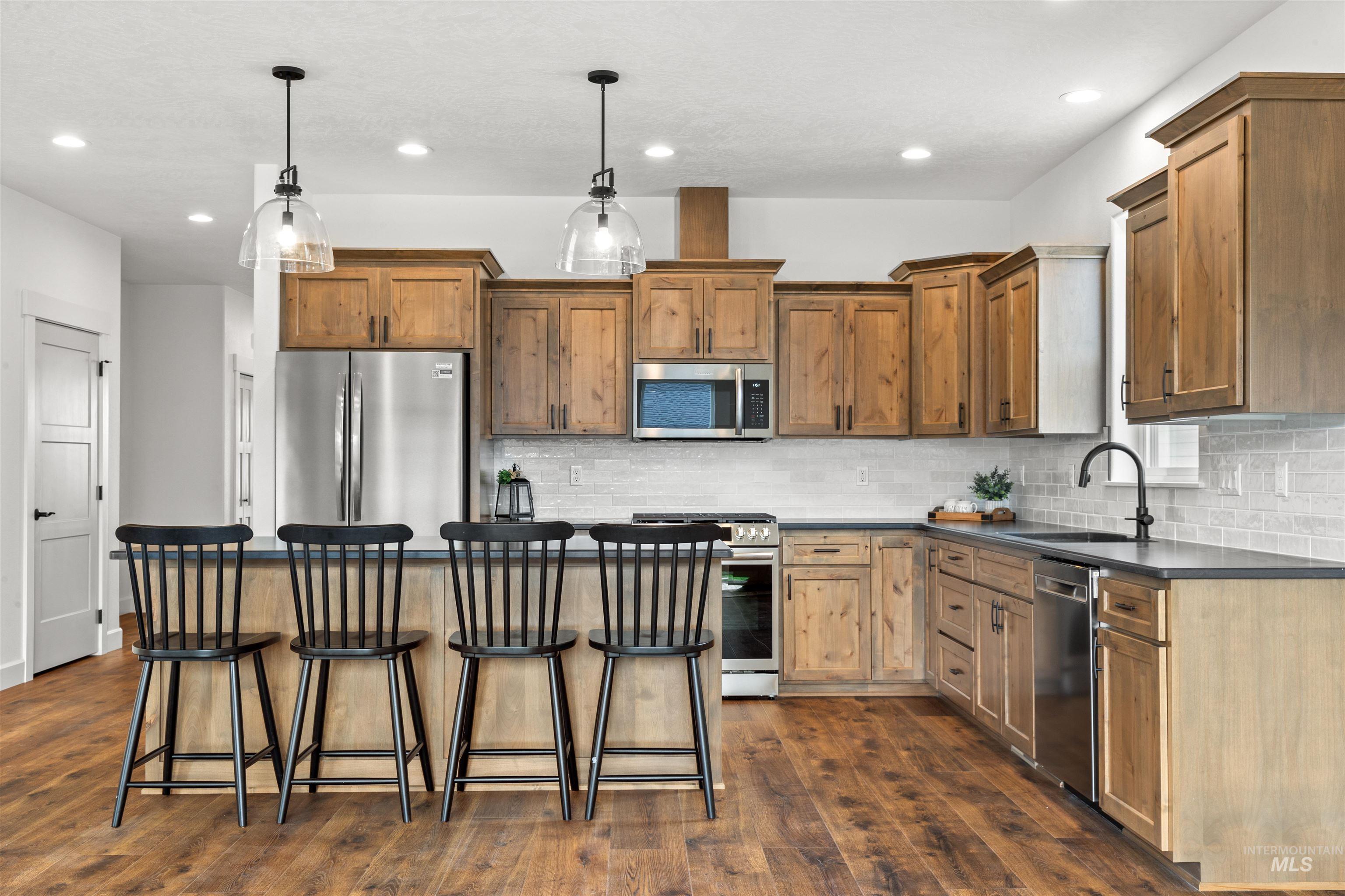 1724 Pathway Court Lewiston, ID 83501 - Photo 11 of 38 Kitchen with a kitchen bar, stainless steel appliances, dark wood finished floors, a kitchen island, and wood finish cabinets