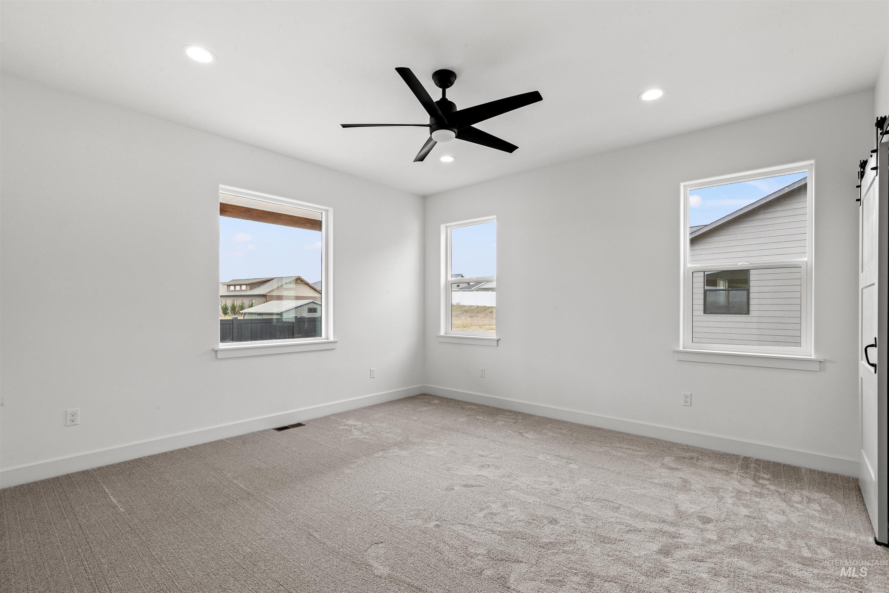 1724 Pathway Court Lewiston, ID 83501 - Photo 19 of 38 Empty room featuring light carpet, healthy amount of natural light, a barn door, and recessed lighting