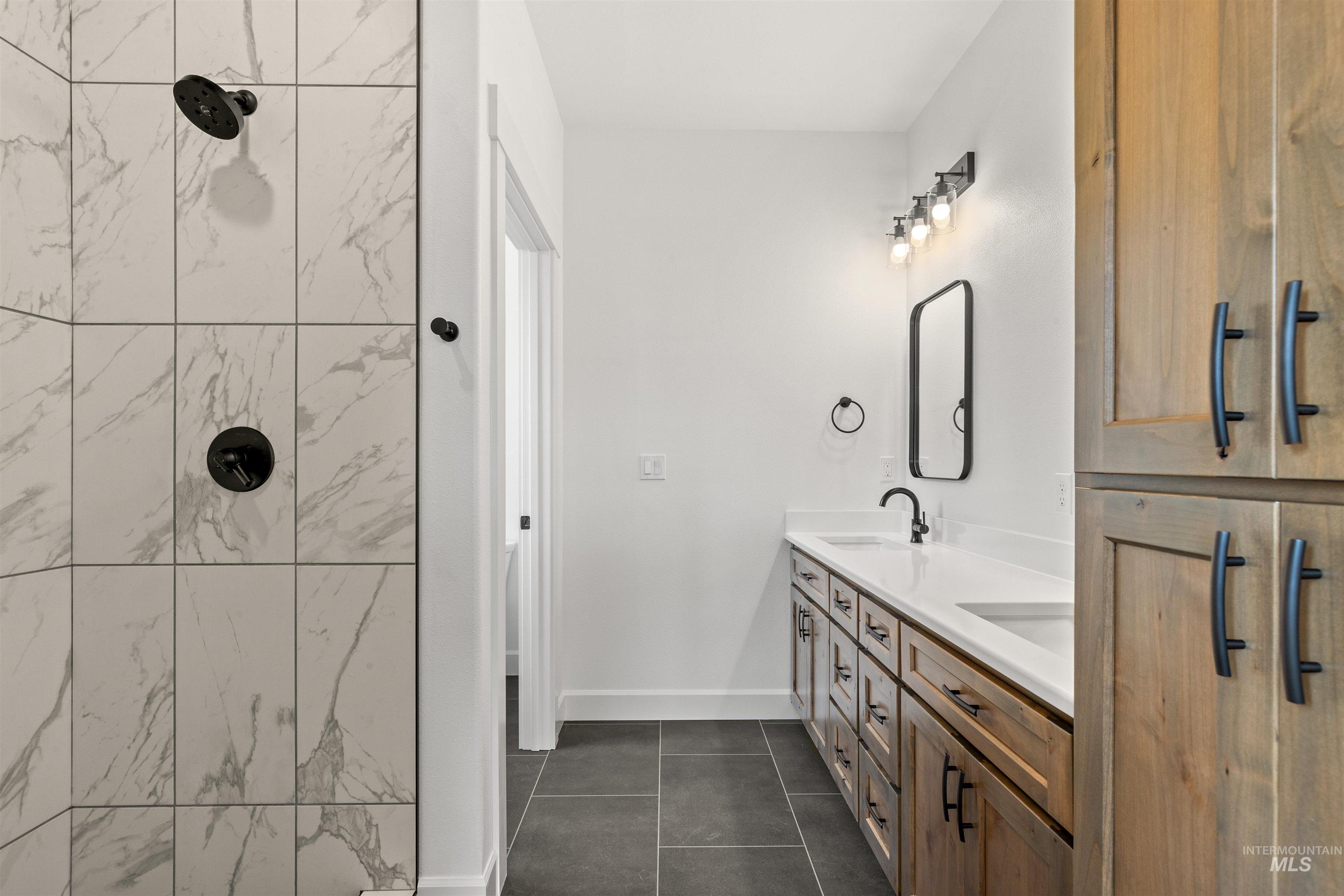 1724 Pathway Court Lewiston, ID 83501 - Photo 22 of 38 Full bath featuring double vanity, a tile shower, and dark tile patterned floors