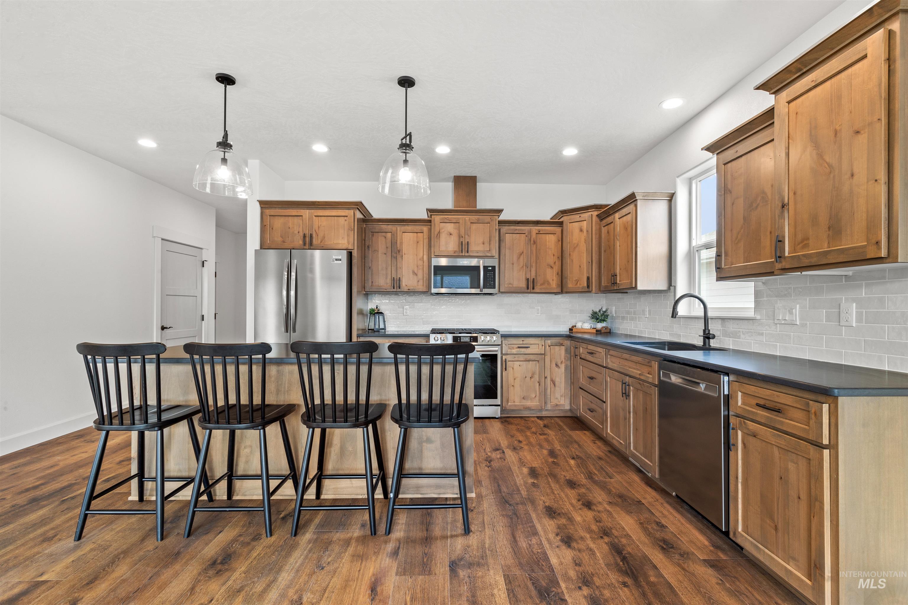 1724 Pathway Court Lewiston, ID 83501 - Photo 4 of 38 Kitchen with a kitchen bar, stainless steel appliances, a kitchen island, decorative light fixtures, and wood finish cabinetry