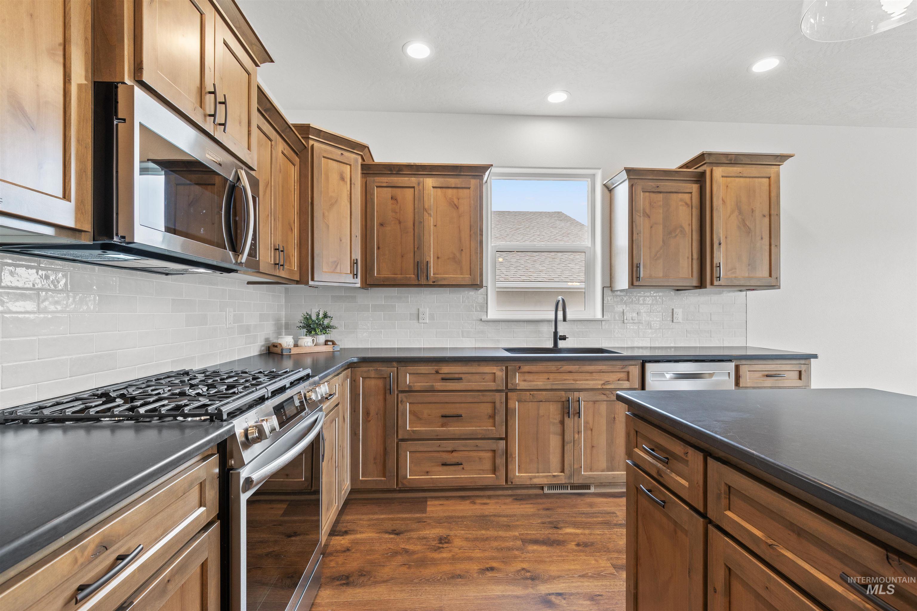 1724 Pathway Court Lewiston, ID 83501 - Photo 5 of 38 Kitchen featuring stainless steel appliances, wood finish cabinetry, dark wood-style flooring, decorative backsplash, and recessed lighting