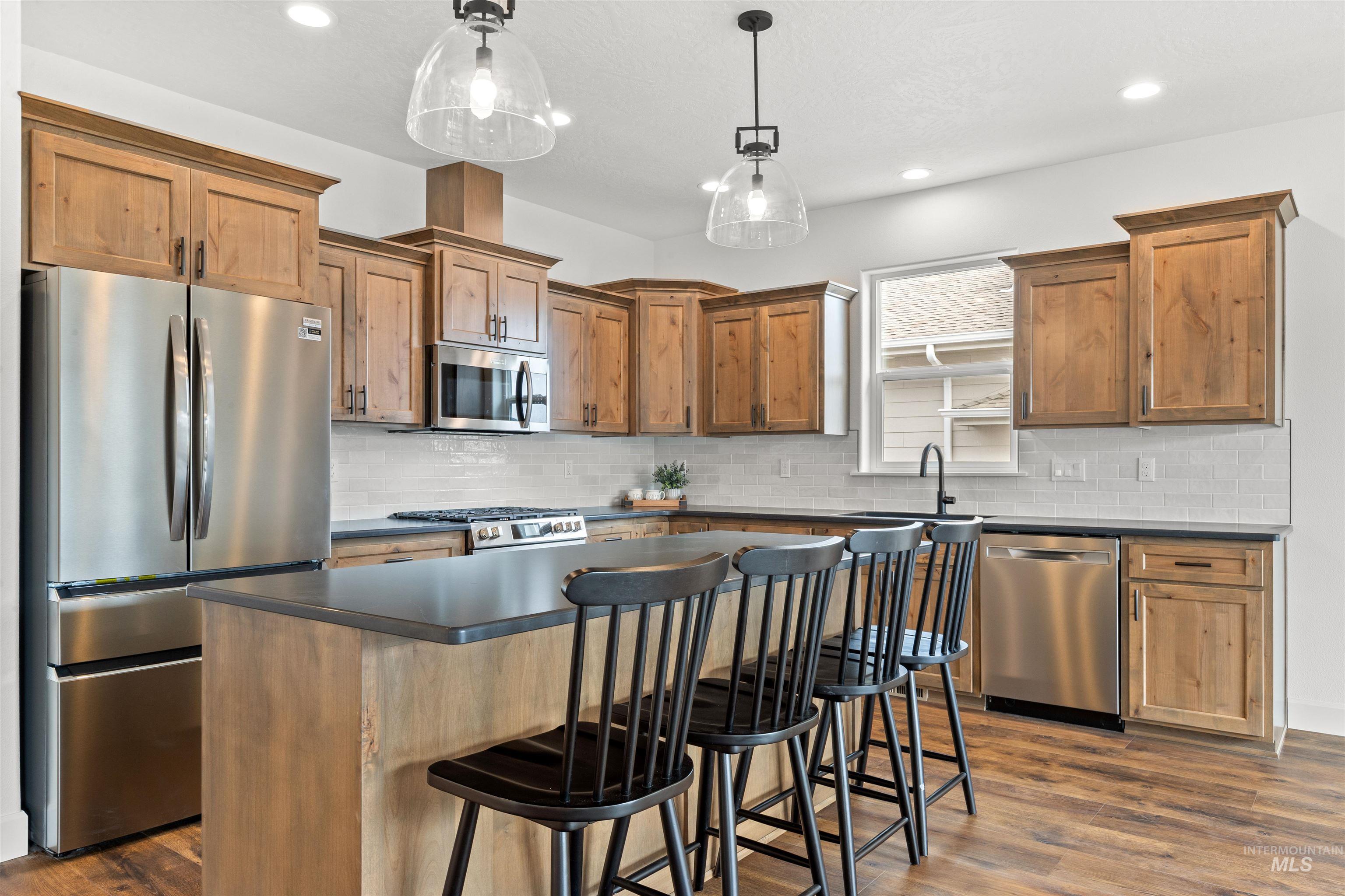 1724 Pathway Court Lewiston, ID 83501 - Photo 6 of 38 Kitchen with stainless steel appliances, a center island, a breakfast bar area, dark wood-type flooring, and wood finish cabinetry