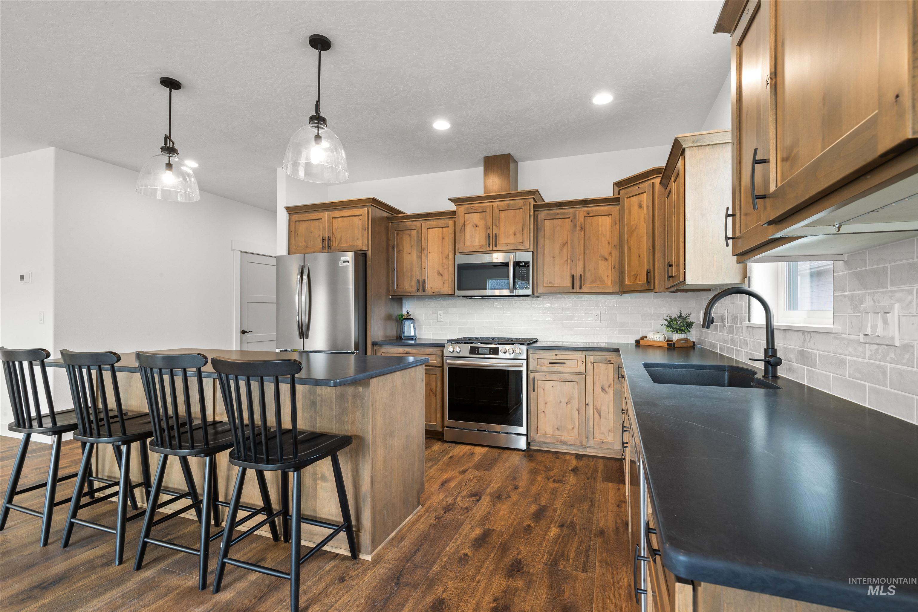 1724 Pathway Court Lewiston, ID 83501 - Photo 7 of 38 Kitchen with dark countertops, a kitchen island, stainless steel appliances, a kitchen bar, and wood finish cabinets