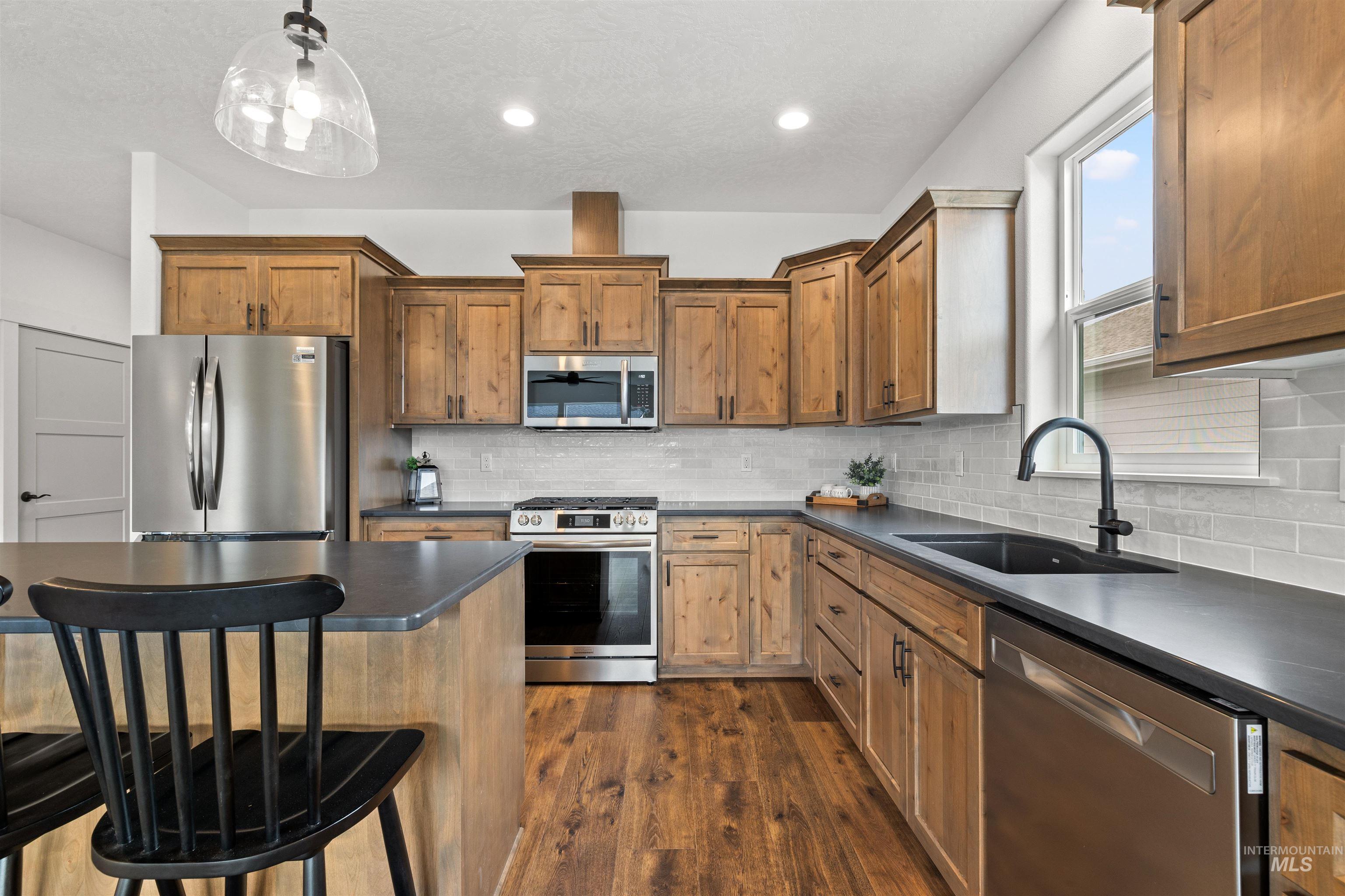 1724 Pathway Court Lewiston, ID 83501 - Photo 8 of 38 Kitchen featuring stainless steel appliances, dark countertops, wood finish cabinetry, dark wood-type flooring, and a breakfast bar