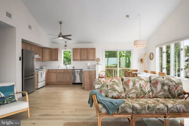 a kitchen with stainless steel appliances granite countertop a refrigerator a sink dishwasher a stove and white countertops with wooden floor