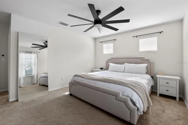 a spacious bedroom with a bed and a ceiling fan