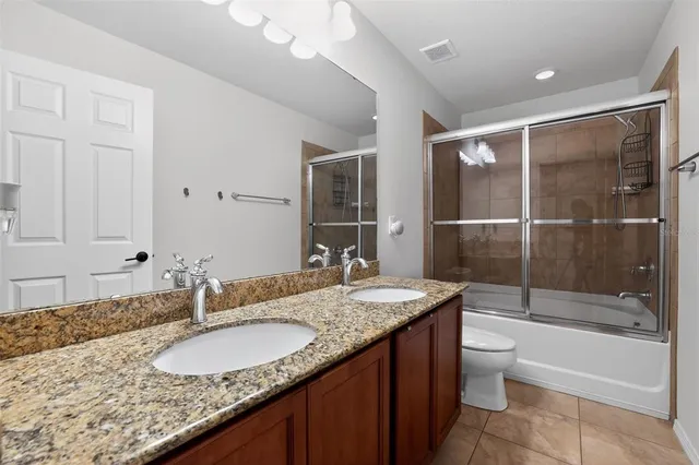 a bathroom with a granite countertop sink and mirror with bathtub