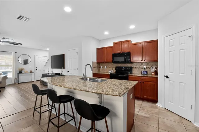 a kitchen with stainless steel appliances granite countertop a stove top oven a sink dishwasher a dining table and chairs with wooden floor