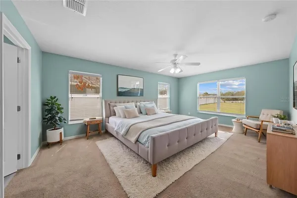 a bedroom with a large bed and potted plant on the dresser