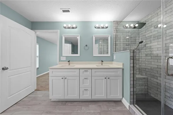 a spacious bathroom with a double vanity sink a mirror and a shower