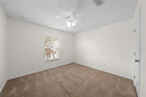 an empty room with windows and fan
