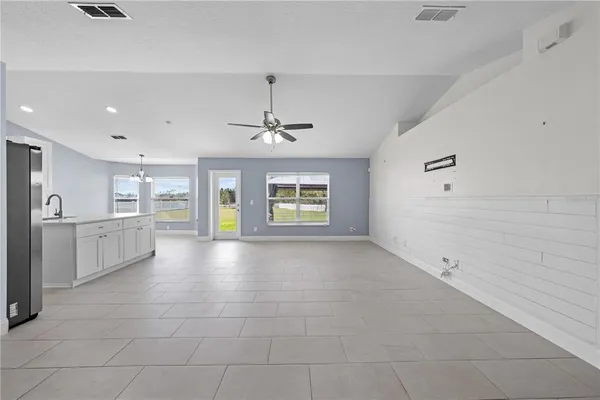 a view of an empty room with kitchen and window