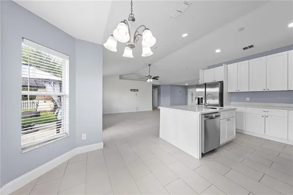 a large white kitchen with a large window a sink and cabinets