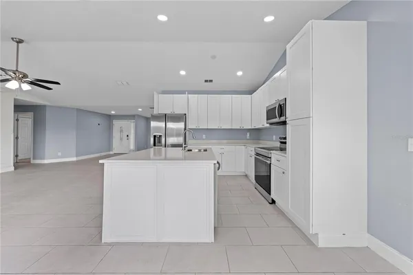 a room with kitchen island a sink stainless steel appliances and cabinets