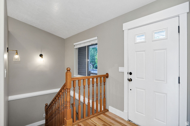 2912 South 1080th Street West Logan, UT 84321 - Photo 4 of 43 Entryway featuring a paneled door with transom windows, wood-finish flooring, and a wood banister