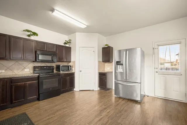 a kitchen with stainless steel appliances granite countertop a refrigerator microwave and stove top oven